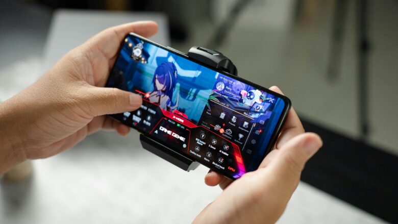 Duas mãos segurando um celular gamer com a tela ligada e rodando um jogo