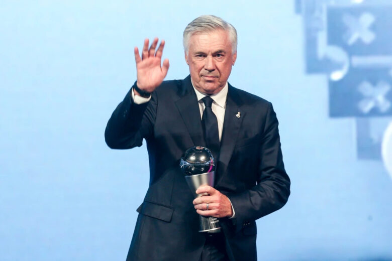 Carlo Ancelotti segurando troféu de futebol e acenando em evento